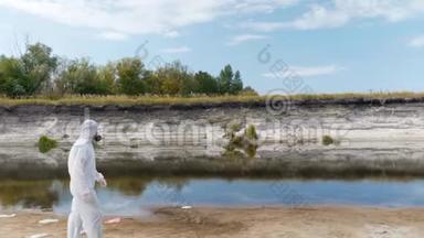 一个穿着防护服和呼吸器的人沿着干河散步，估计污染的程度